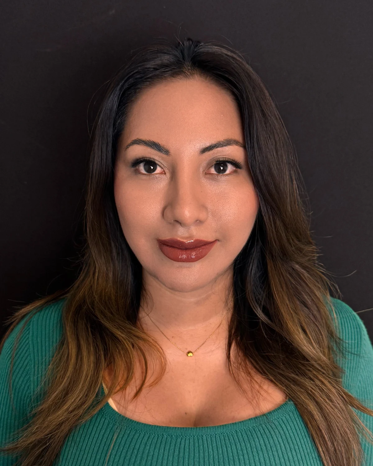 La misma paciente de frente después del lifting endoscópico, con blusa verde sobre fondo oscuro