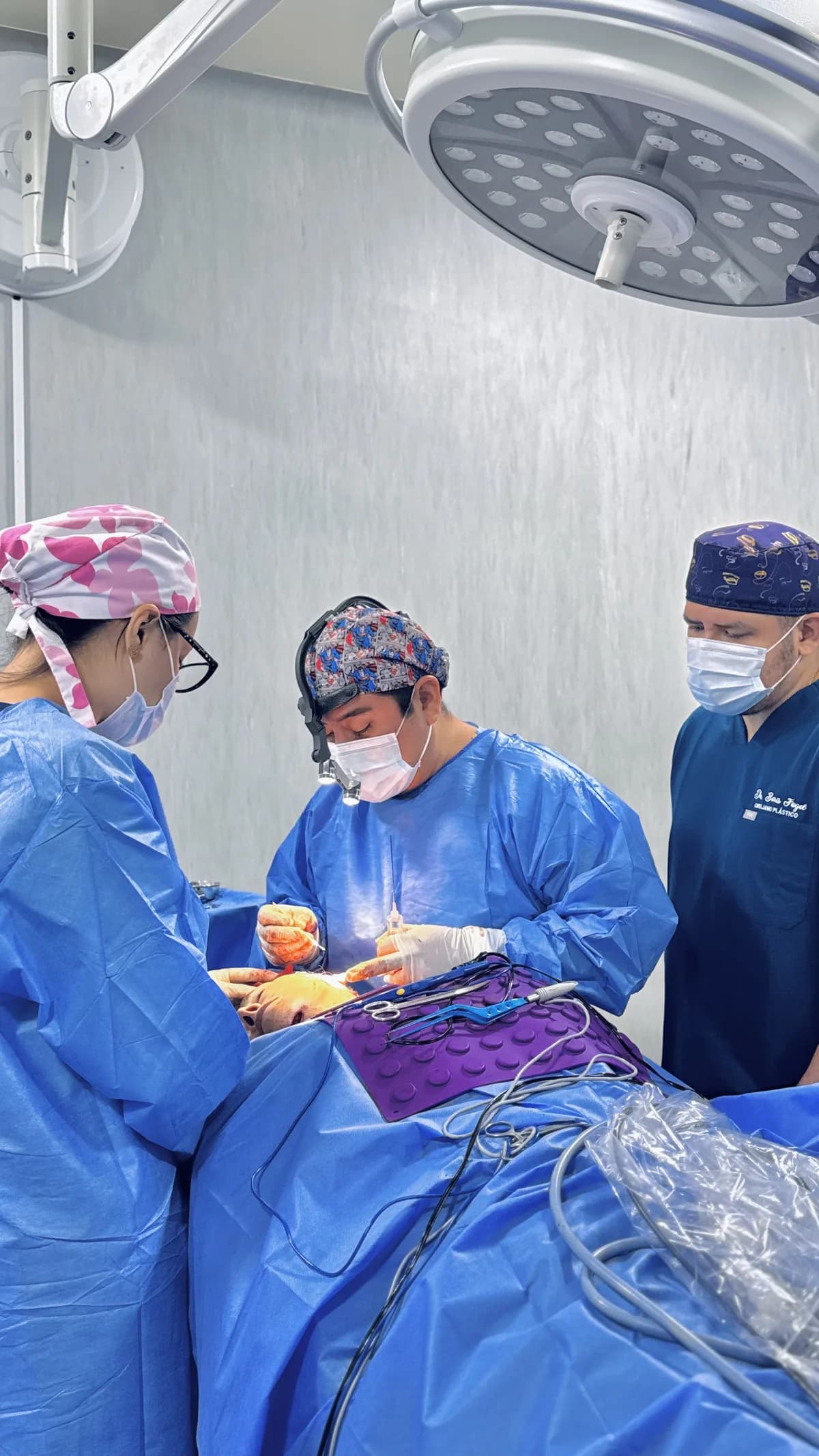 Dr. Freddy Castillo con lupas quirúrgicas durante una cirugía observada por cirujanos del programa