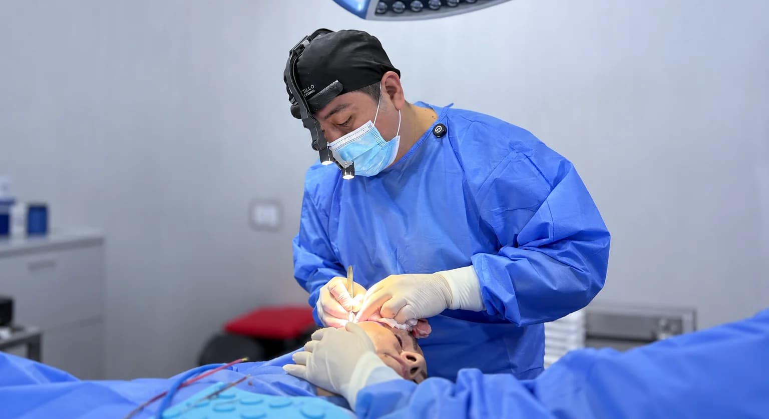 Dr. Freddy Castillo, cirujano plástico, operando en quirófano durante una cirugía de lifting facial en Lima